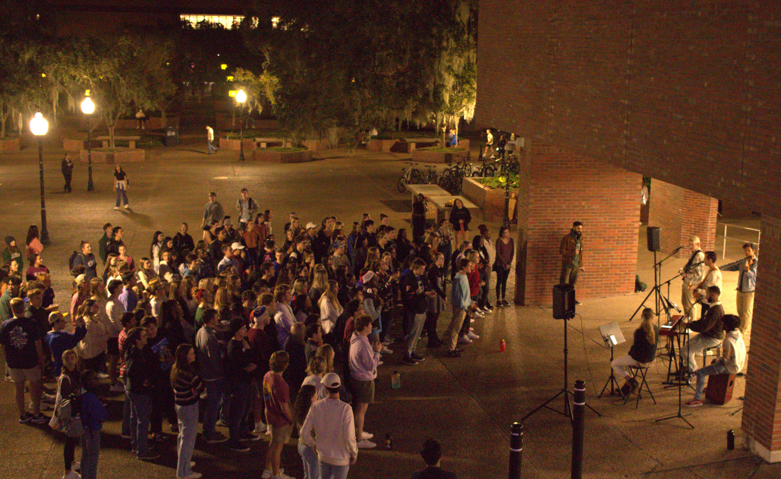 Students gathered around musicians for outdoor worship on campus