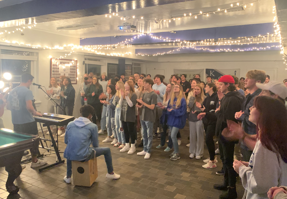 Students singing with musicians at an indoor worship night